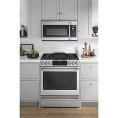 a silver stove top oven sitting inside of a kitchen next to white cupboards and counter tops