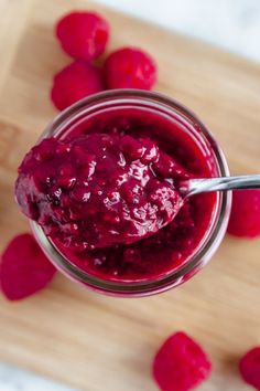 raspberry sauce in a small glass jar with a spoon on a cutting board