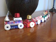 a train made out of toilet paper rolls on a wooden table next to a vase