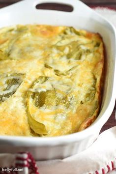 a casserole dish with cheese and green peppers in it on a white cloth