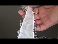 someone is stitching together some string and bead to make a christmas tree ornament