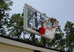 a basketball hoop is hanging from the side of a house with trees in the background