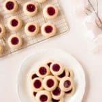 small pastries are arranged on a plate next to a tray of cookies and flowers