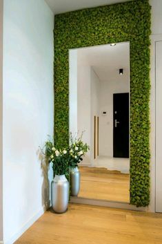 two vases filled with flowers sitting on top of a wooden floor next to a wall