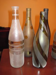 four different colored vases sitting on top of a wooden table