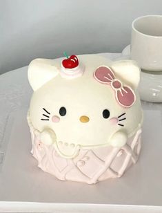 a hello kitty cake sitting on top of a table next to a cup and saucer