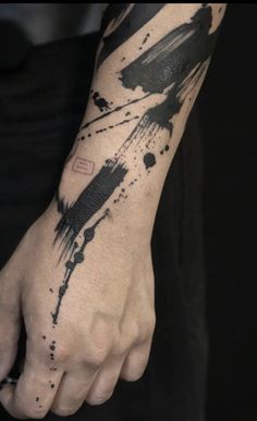 a man's arm with black ink splattered on it and his hand