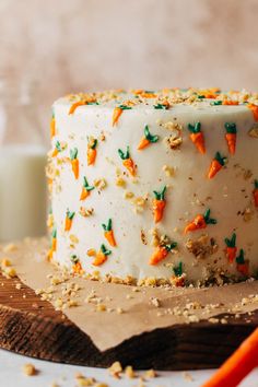 a carrot cake with white frosting and sprinkles on a cutting board