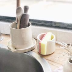 a cup with some spoons in it sitting on a window sill