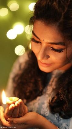 a woman holding a lit candle in her hands