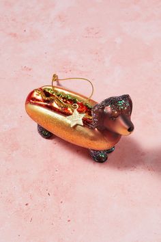 a hot dog ornament on a pink surface