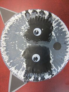 two black and white paper plates with eyeballs on them sitting on a red surface