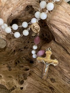 Hand picked with care to create a beautiful piece.  I love the gold with the light pink and white.  Such a purity and simple elegance to the rosary with a substantial weighted crucifix.  The "Our Father" beads are pink glass and the "Hail Mary" beads are white shell.  I always prefer the "Our Father" and "Hail Mary" beads to be a different shape or size so one can go into deep prayer with their eyes closed and know when they are at the next mystery by touch alone.  All parts are new on this rosa White Spiritual Cross Pendant Jewelry, White Spiritual Crucifix Jewelry, Spiritual White Crucifix Jewelry, White Crucifix Rosary With Miraculous Medal, White Spiritual Rosary With Miraculous Medal, Spiritual White Rosary With Miraculous Medal, White Spiritual Cross Jewelry And Charms, White Spiritual Crucifix Necklace, White Crucifix Spiritual Necklace