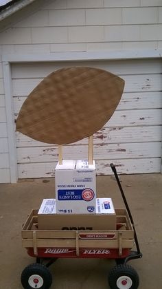 a red wagon filled with boxes and a wooden board on top of it's wheels