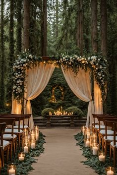 an outdoor wedding ceremony with candles and greenery on the aisle, surrounded by tall trees