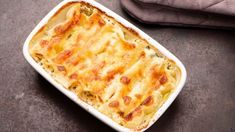 a casserole dish with cheese and spinach in it on a table next to a cloth