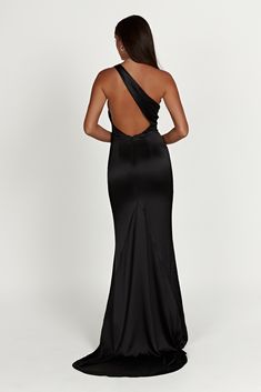 the back of a woman wearing a black evening gown with one shoulder and an open back