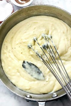 a pan filled with batter and whisks on top of a marble countertop