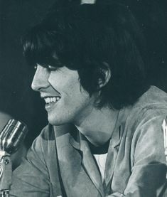 a black and white photo of a person sitting at a table with a microphone in front of him