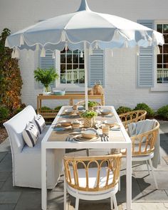 an outdoor dining table with chairs and umbrella