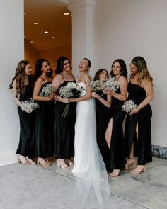 a group of women standing next to each other in front of a white wall holding bouquets