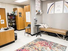 a room with a rug, bookshelf and desks