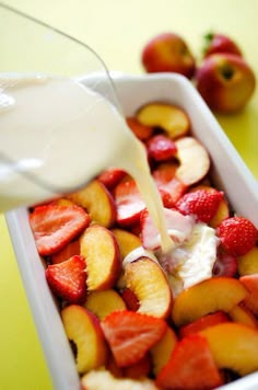 someone pouring milk into a dish full of fruit