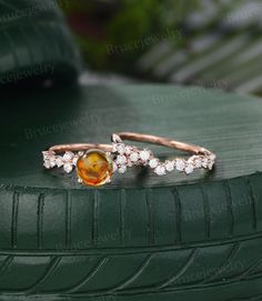 two gold rings with an orange stone and white diamonds on top of a green tire