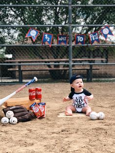 a baby sitting on the ground next to a baseball bat