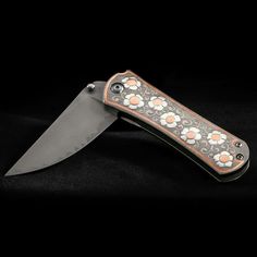 a knife that is sitting on top of a black surface with orange and white flowers