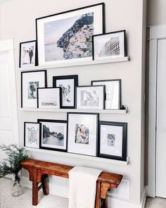 a bunch of pictures are hanging on the wall next to a bench with a towel draped over it