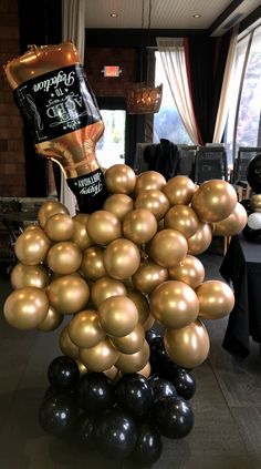 a bunch of black and gold balloons in the shape of a wine bottle sitting on top of a table