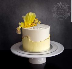 a white cake with yellow flowers on top sitting on a plate in front of a black background