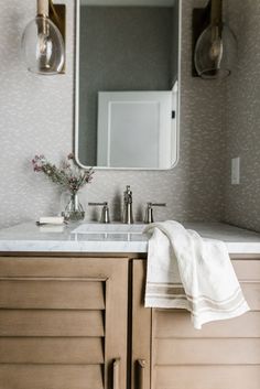 a bathroom vanity with a large mirror and two lights on the wall next to it