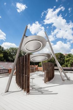 an artistic sculpture in the middle of a large open area with wooden poles and circular sculptures