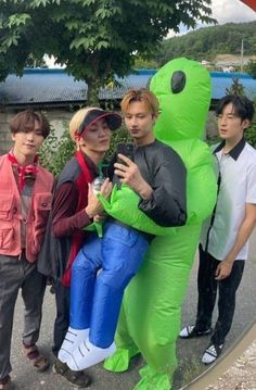 some people are posing for a picture with a big green monster in front of them