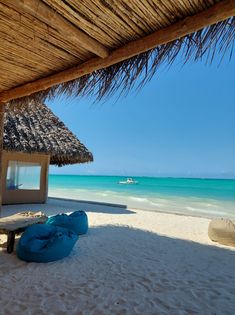 there is a blue bag on the beach next to an umbrella and some water in the background