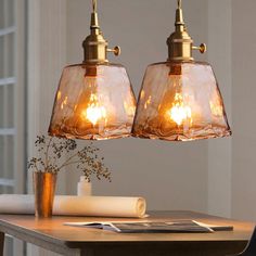 two lights hanging over a wooden table in a room