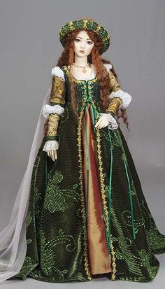 a doll dressed in green and gold with a veil on her head, wearing a dress