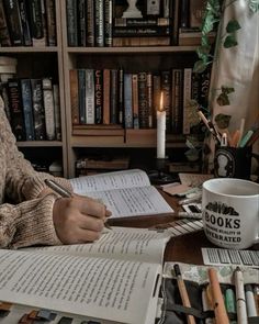 a woman sitting at a table with books and coffee mug in front of her, holding a pen