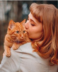 a woman is kissing a cat with her face close to the camera while she's wearing a suit