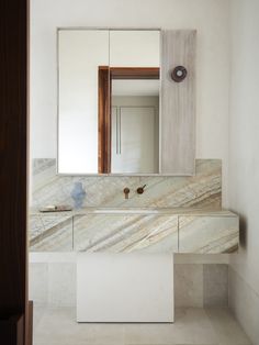 a bathroom with marble counter tops and white walls, along with a large mirror on the wall