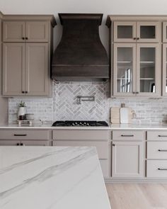 a kitchen with marble counter tops and gray cabinets