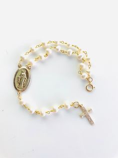 "This is a stunning rosary inspired bracelet made with freshwater pearls in 14k gold filled!   A large 1\" gold filled Miraculous medallion and 3/4\" gold filled cross charm make this rosary bracelet stand out!   Bracelet may be ordered in a 6.5-9.5\" length.  Priced accordingly, you choose size.  Comes nicely boxed, the perfect gift! May be ordered in 925 sterling silver or 14k rose gold filled, not shown." Adjustable Gold Rosary Bracelet With Pearl Charm, Adjustable Gold Pearl Rosary Bracelet, Gold Pearl Rosary Bracelet With Round Beads, Gold Bracelets With Round Beads For First Communion, Handmade Gold Jewelry For First Communion, Gold Pearl Rosary Bracelet With Pearl Charm, Handmade Gold Bracelets For First Communion, Handmade Gold Bracelet For First Communion, Gold Spiritual Rosary Bracelet For First Communion