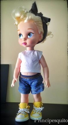 a doll with blonde hair and blue eyes is standing on a black table next to a white wall