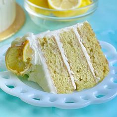 a slice of cake with white frosting and lemons on the side sitting on a plate