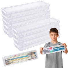 a young boy holding up a plastic box with pencils in it and several other boxes behind him