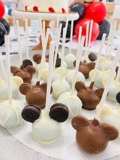 mickey mouse cake pops are arranged on a plate with white and brown candy sticks sticking out of them