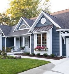 a blue house with white trim and flowers in the window boxes on the front door