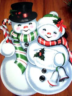 three snowmen with hats, scarfs and candy canes are standing next to each other